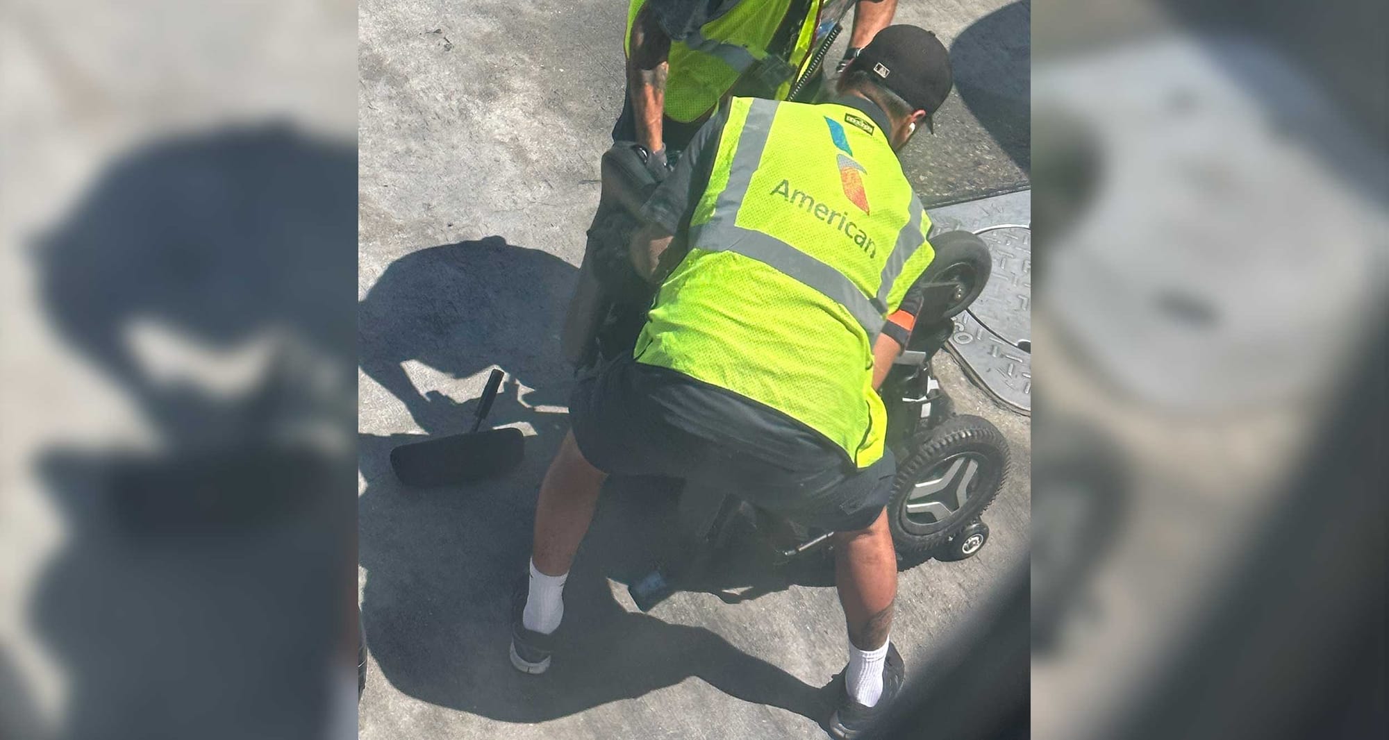 Airline personnel handling wheelchair after dropping it from airline baggage loader.