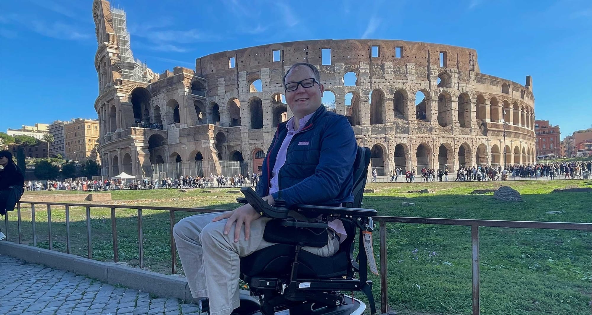 John seated in his wheelchair outside of the Colosseum in Rome.