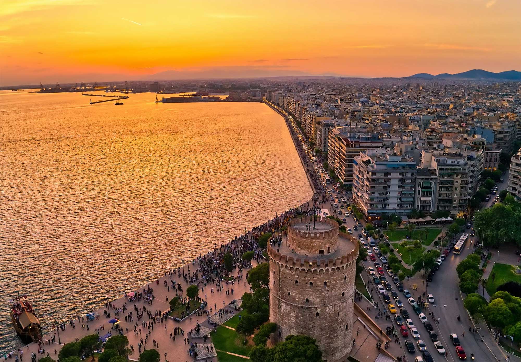 Overhead view of Thessaloniki coastline with circular tower and pedestrian area along waterfront.