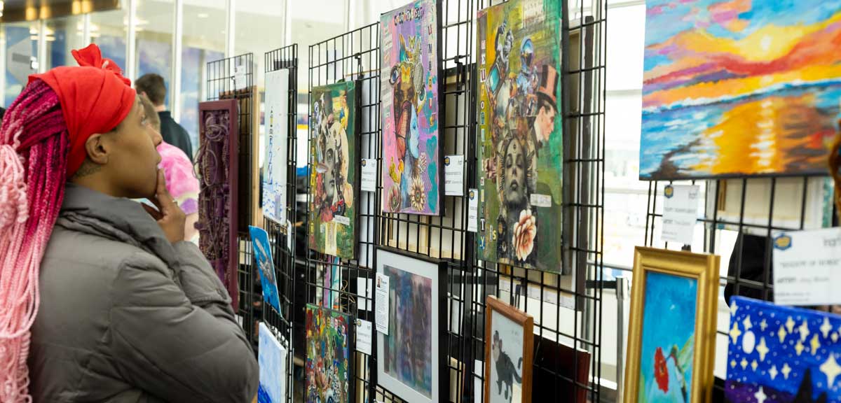 Woman viewing art pieces on display at Indianapolis Airport.