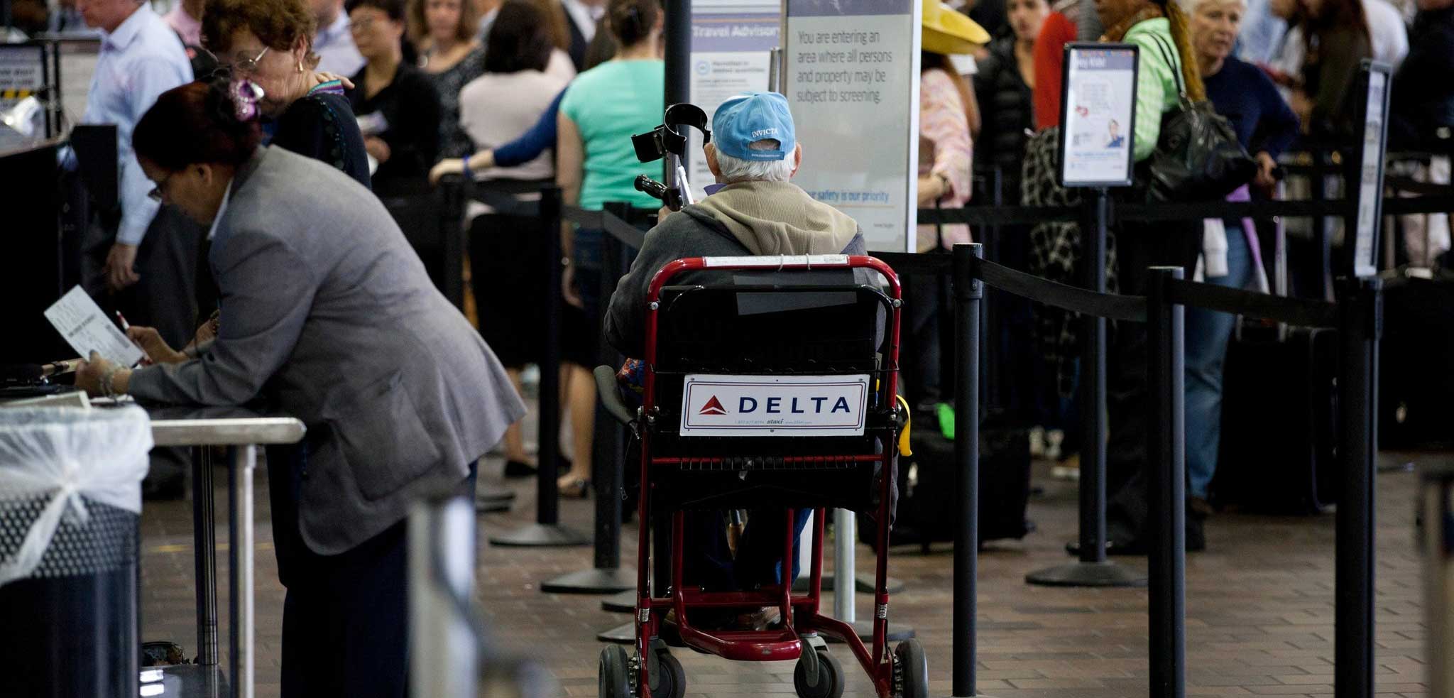 Older man seated in a wheelchair at the airport check-in area.