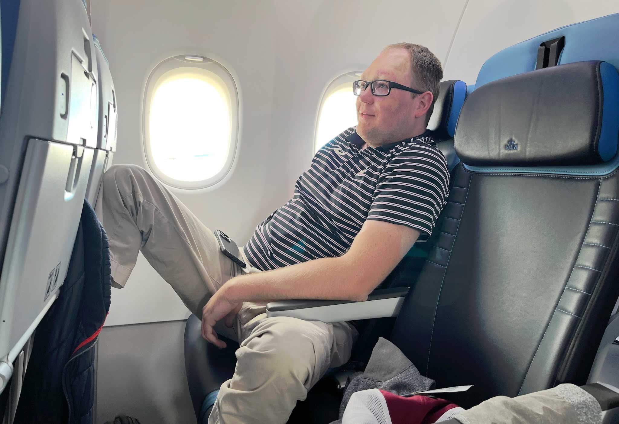 John relaxing on the airplane with a bit of a smirk on his face.