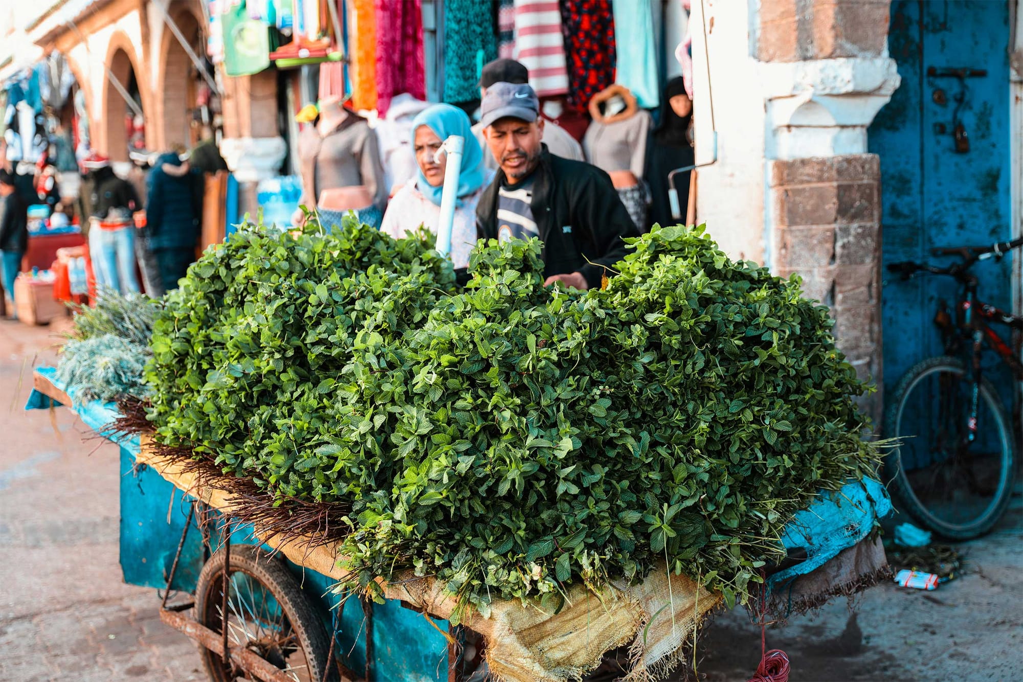 Vendor selling vegetables and leafy greens from a cart.