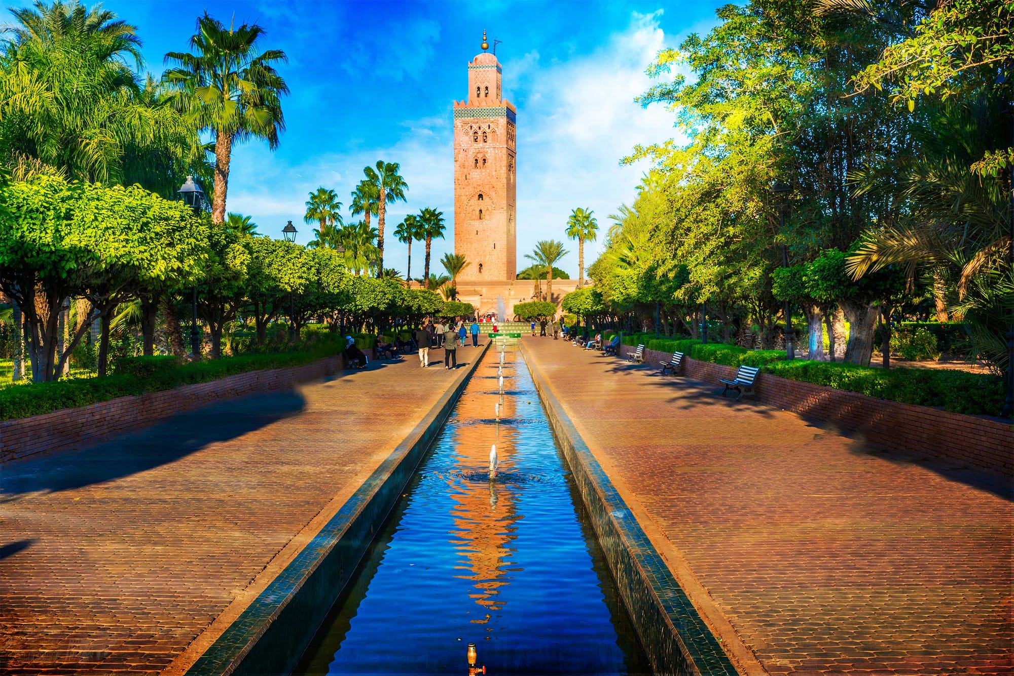 Mosque tower overlooking finely manicured park with water fountains.