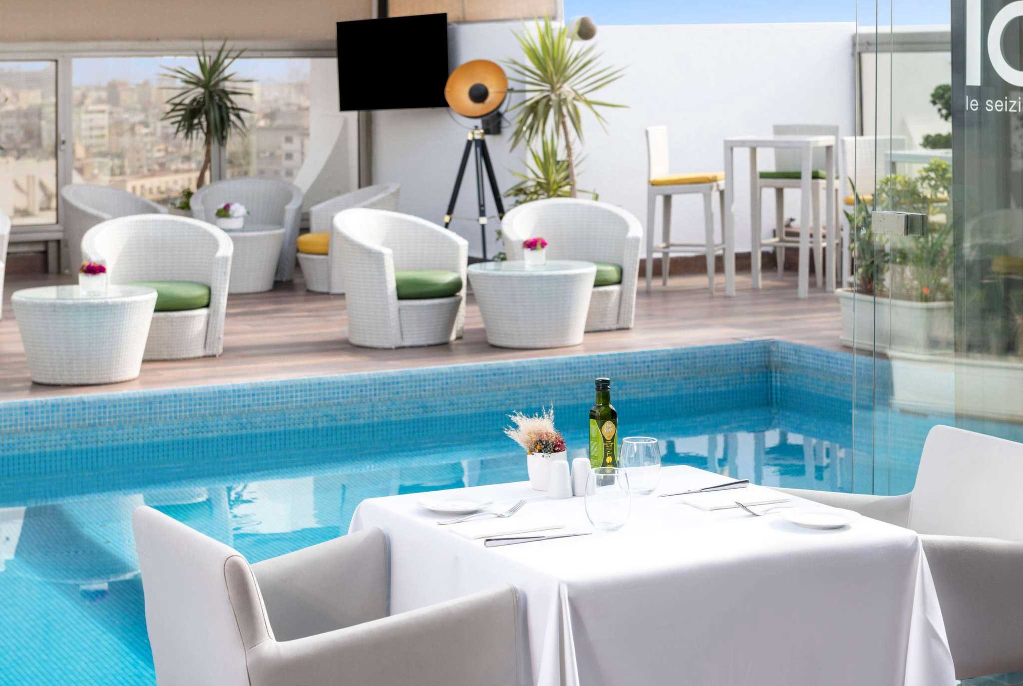 Dining table next to pool on rooftop of luxury hotel in Casablanca.