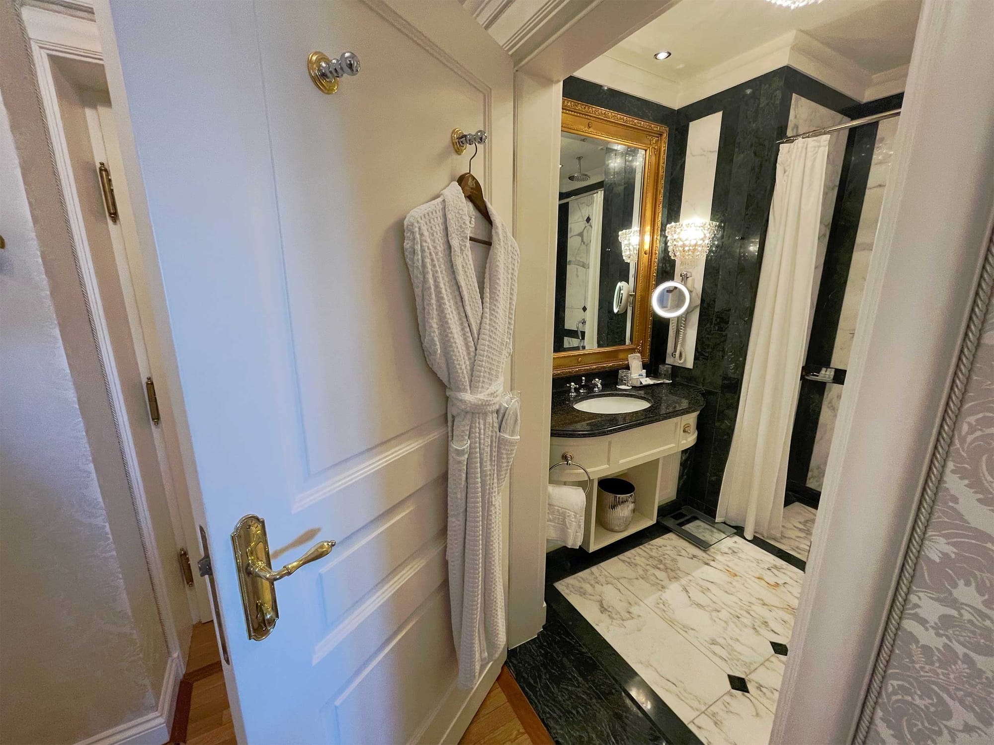 Door ajar looking into marble bathroom.