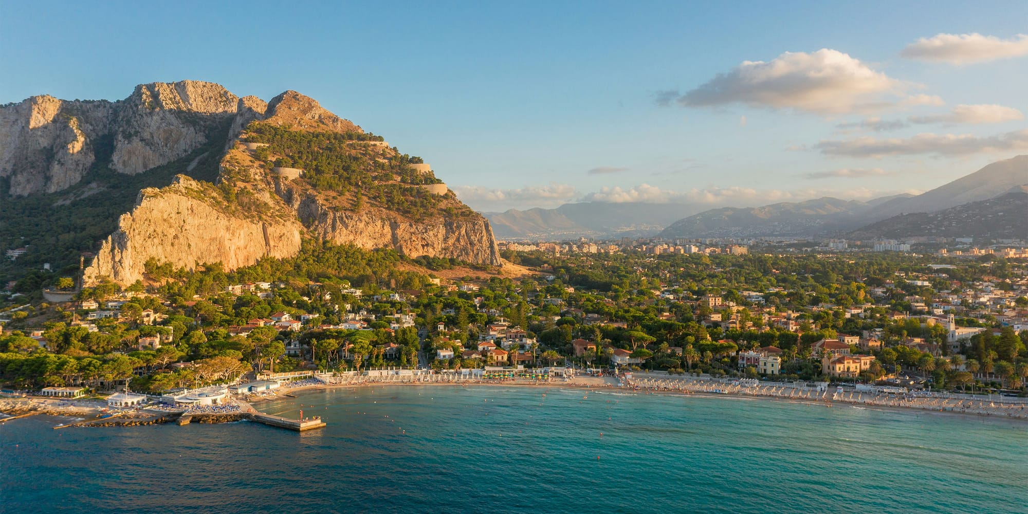 Coastal city along Mediterranean with a large rock formation near the coast.