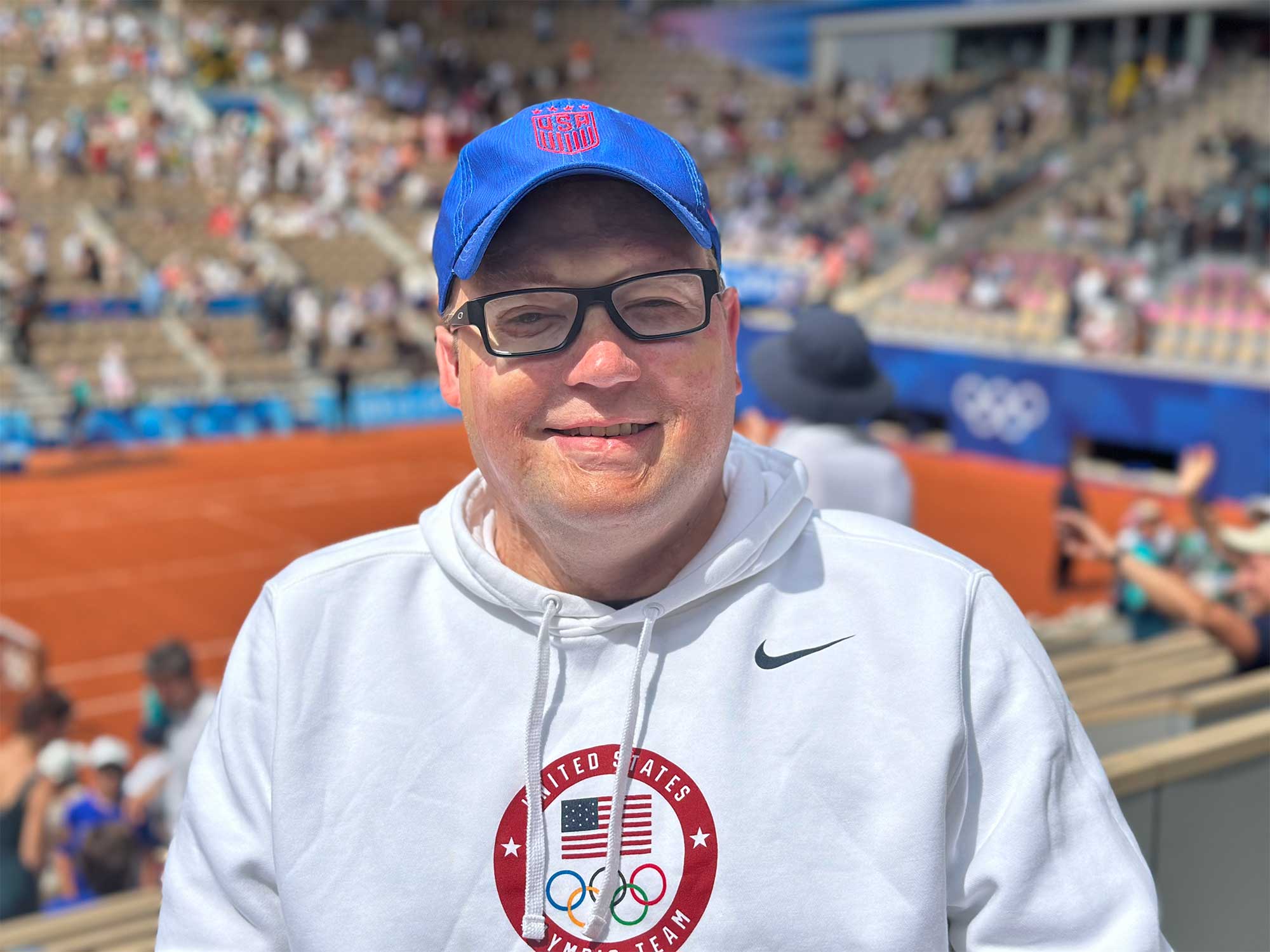 John wearing a hoodie with the United States Olympic Team logo at the Roland Garros tennis court in Paris.