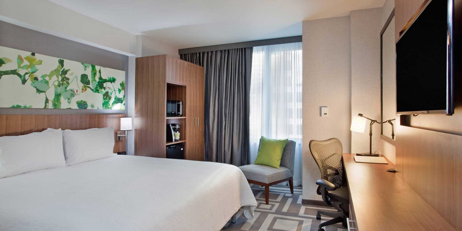 Hotel room with bed, desk, television, chair and more.