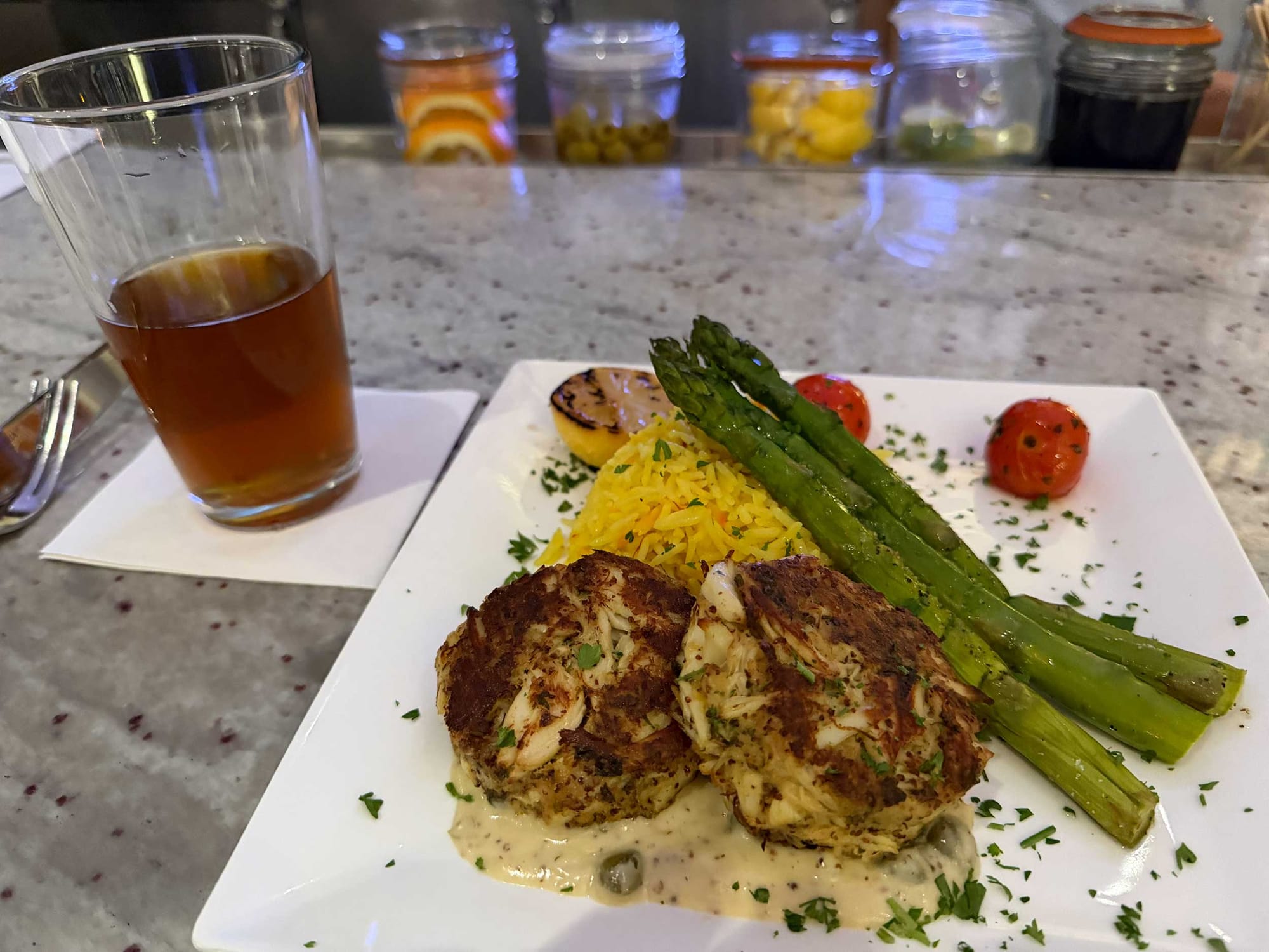 Crab cakes, rice and asparagus on a plate.
