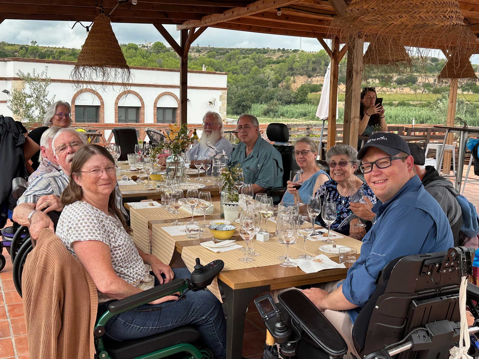 Wheelchair users seated around a table in the Spanish countryside.