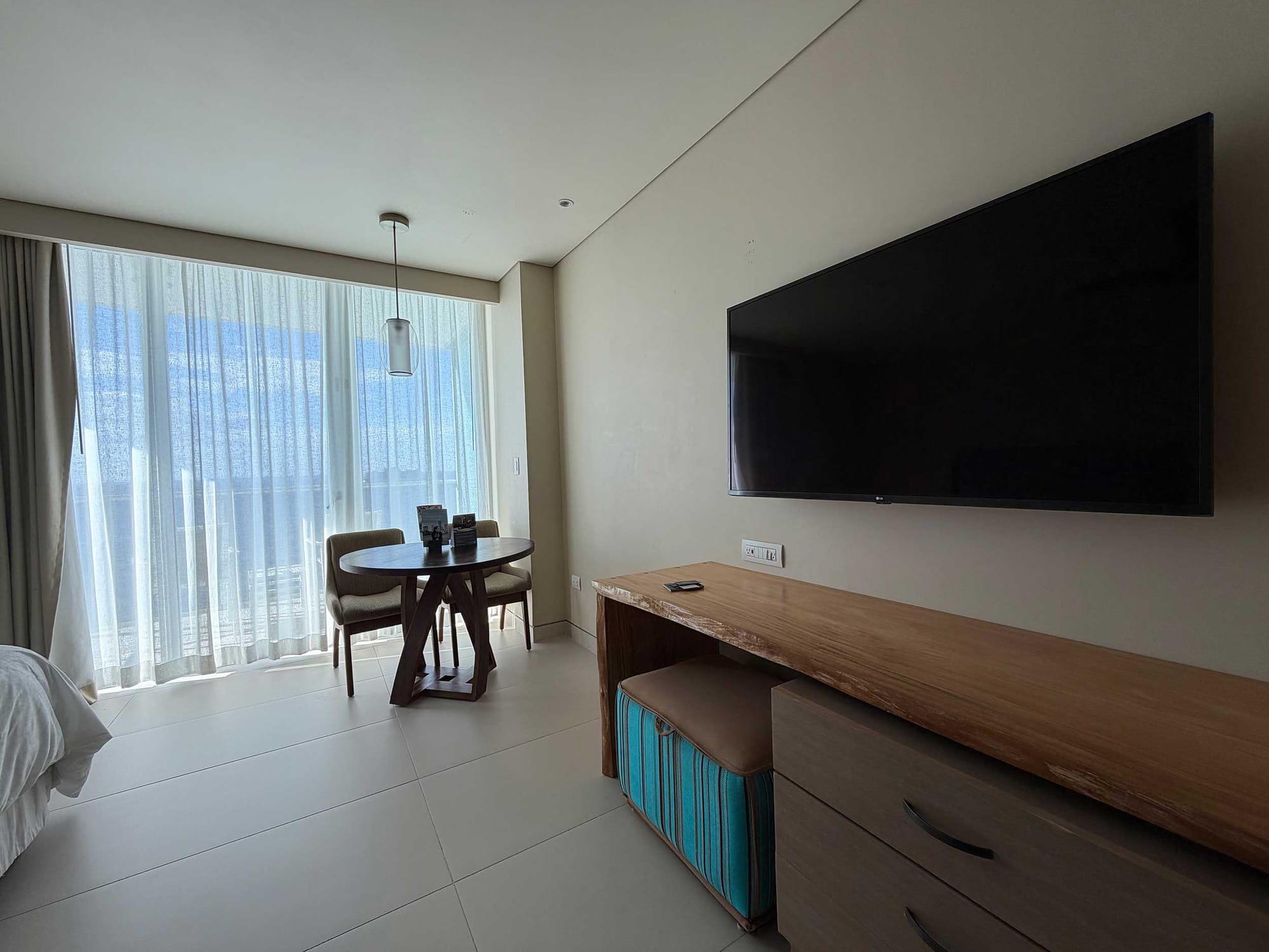 Wall-mounted television, desk and table.