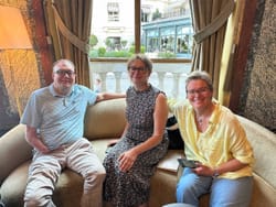 John seated on a sofa in a cafe with two women in Monaco.