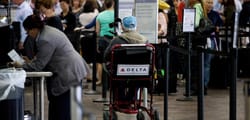 Older man seated in a wheelchair at the airport check-in area.