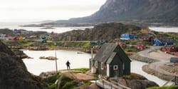Houses spread across a rocky and hilly area in a Greenland village.