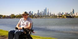 John pictured in front of Melbourne, Australia skyline wearing a cowboy hat.