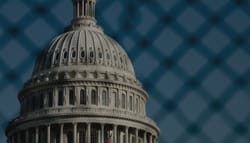 Dome of the United States Capitol Building, seen through a chain-link fence.