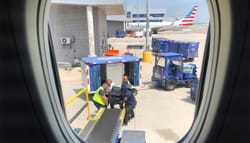 American Airlines baggage handlers lifting wheelchair at JFK Airport.