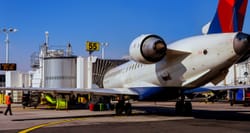 Delta airplane connected to airport jet bridge.