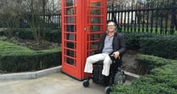 Wheelchair user next to red telephone booth in London.