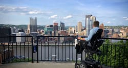 Power wheelchair in front of city skyline.