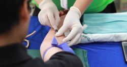 Nurse drawing blood from a man's arm.