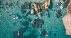 Aerial view of kayaks and boats on the water near a waterfall.