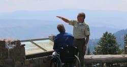 Park ranger speaking with a wheelchair user at an overlook inside a National Park.