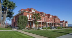 Exterior of The Lodge at the Presidio, a three story brick building sitting in front of the Golden Gate Bridge.