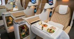 Emirates business class seat, with meal presented on tray table.