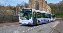 City bus moving along roadway in Scotland.