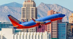 Southwest Airlines Boeing 737 inn takeoff climb; tall buildings in background.