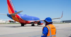 Airline employee watches from tarmac as Southwest Airlines jet taxis away.