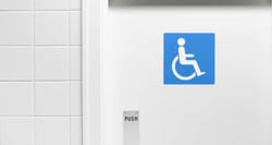 Blue wheelchair icon on white door to bathroom.