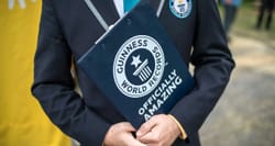 Man in suit holding folder with Guinness World Records logo.