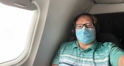 John takes selfie during flight while wearing face mask.