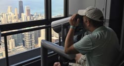 Wheelchair user looking at city skyline through accessible viewfinder.