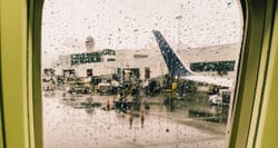 Rain drop covered airplane window, looking out to airport terminal.