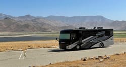 Winnebago Inspire parked in front of lake and mountains.