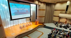 RedCabin logo projected on screen, hanging over large meeting hall with multiple levels.