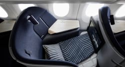 Finnair business class seat in lay flat bed mode with pillow and blanket.