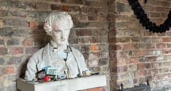 Stone bust of Edgar Allan Poe on a pedestal in the outdoor shrine to the author at the Poe Museum