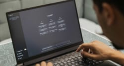 Person sitting at desk with laptop computer, chat GPT website displayed on screen.