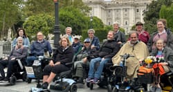 Group of wheelchair users in front of Royal Palace of Madrid.