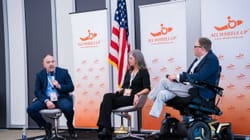 John seated on stage with two panelists at the All Wheels Up Global Forum.