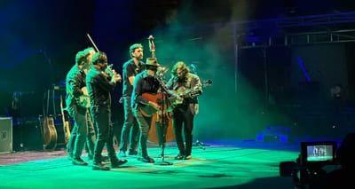 Musicians gathered in a close circle around a microphone onstage.