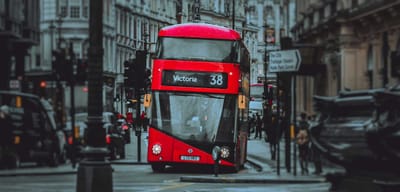 Double decker London city bus driving on roadway.
