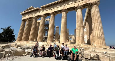 Group of wheelchair users in front of the Parthenon with its enormous marble pillars on the Acropolis hill in Athens, Greece.