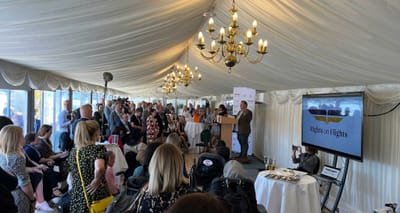 Large group gathered under a tent on a terrace.