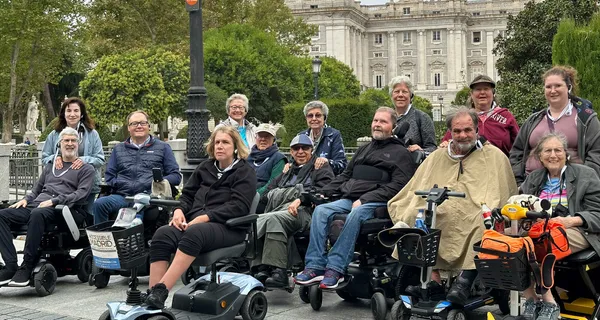 Group of wheelchair users in front of Royal Palace of Madrid.